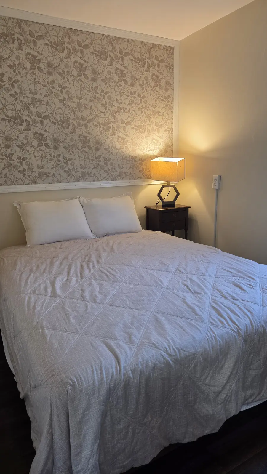 Ugly Kitchen bedroom with floral accent wall and bedside lamp