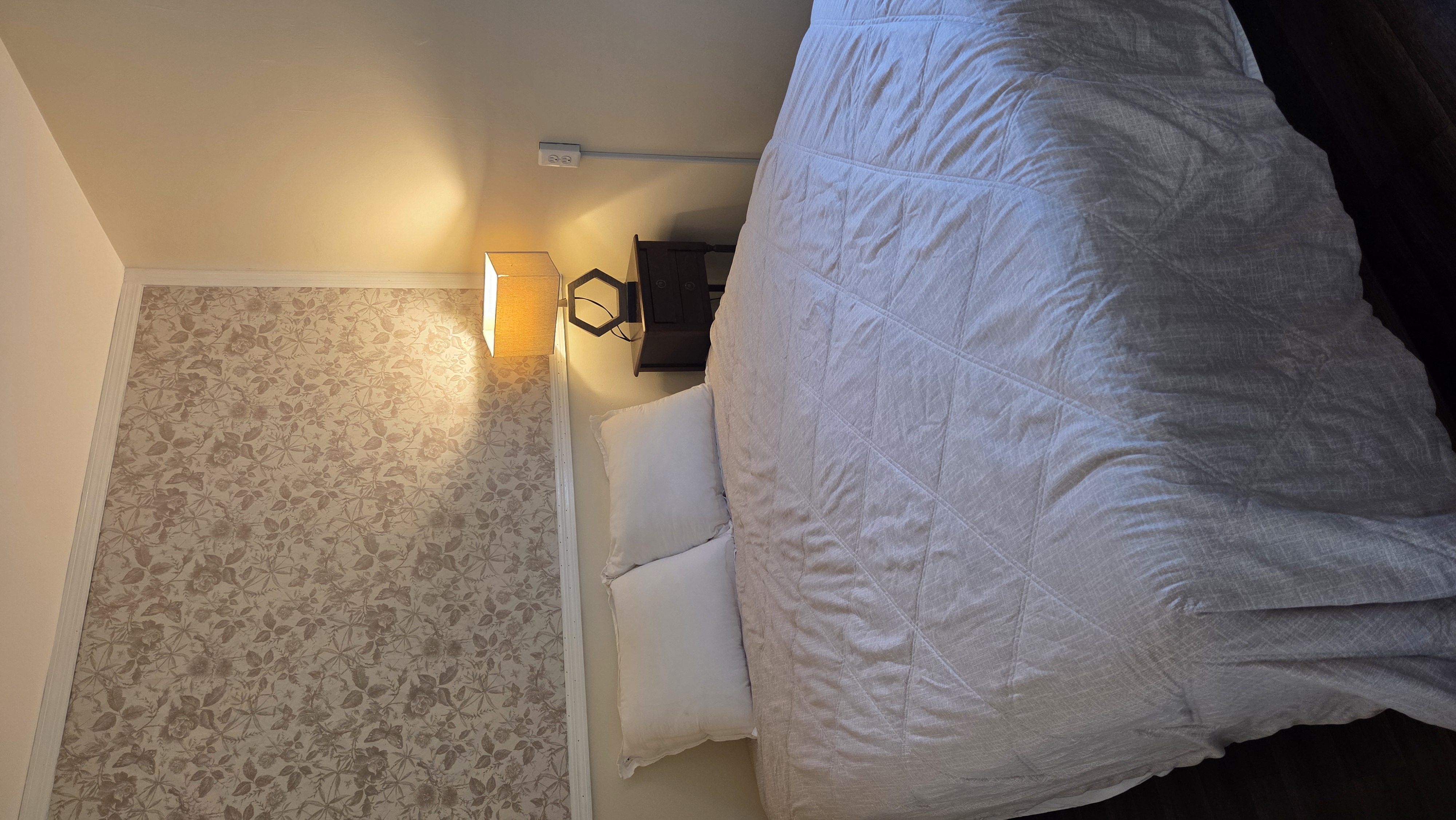 Ugly Kitchen bedroom with floral accent wall and bedside lamp